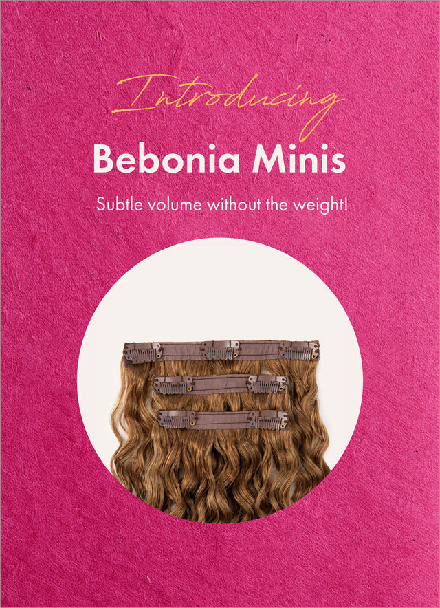 Front view of Bebonia Minis with wavy clip in extensions promoting subtle volume without the weight on a pink background