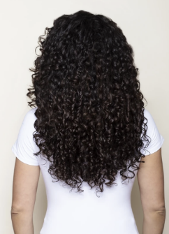 Rear view of curly hair extensions showcasing mid-back length with a white background